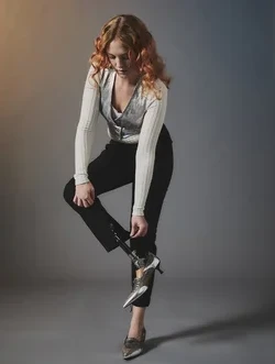 Woman wears black trousers with zip at ankle showing her prosthetic leg and silver heeled shoes